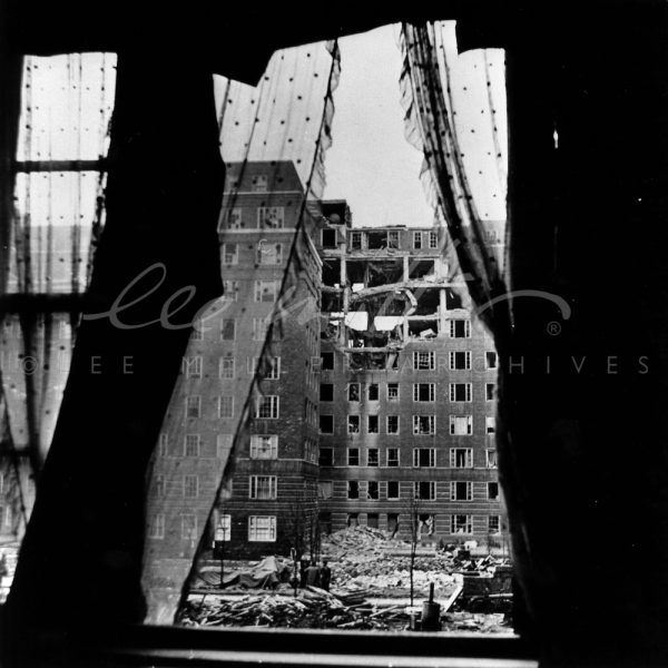 Black and white. View from interior to bomb damaged apartment block.