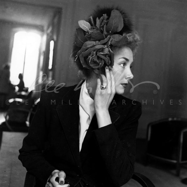 Black and white. Close up of model in hat with large rose.
