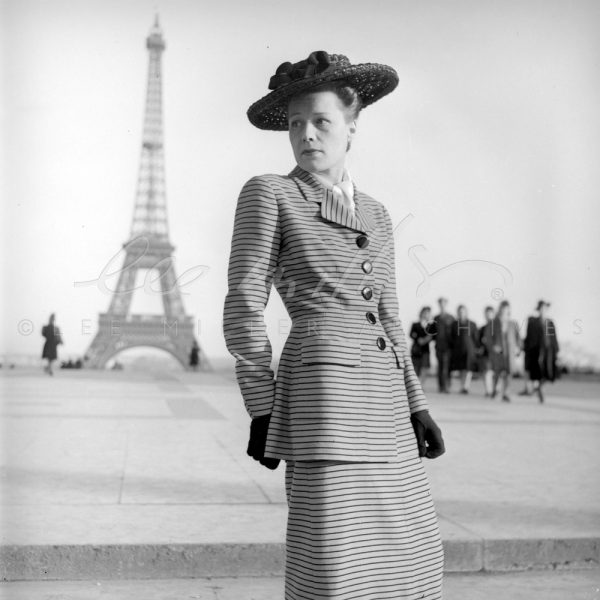 Black and white. Model in suit in foreground, Eiffel tower in background.